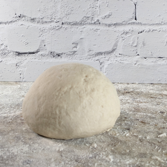 A dough ball ready to be rolled out into a pizza from this easy pizza dough recipe 