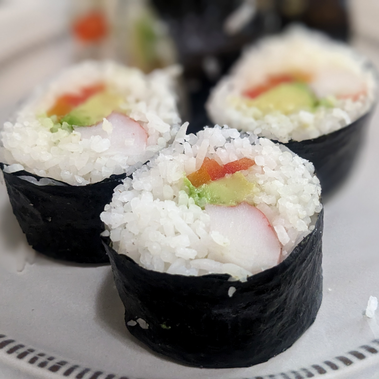 Plated Zesty california rolls featured in this Sushi Rice Recipe. Featuring vibrant red and orange pepper and creamy avocado.